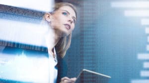 Woman economist holding a notebook and peers at stylized graphs and charts of economic performance