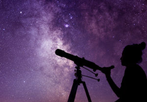 Astronomy Colleg Major - Woman looking through a telescope at milky way stars