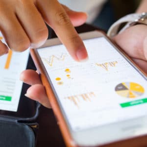 Business Management & Administration Career Cluster image of woman analyzing financial information on a phone app