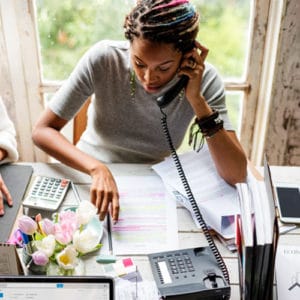 Editor Career - Female editor on the phone looking over a written manuscript