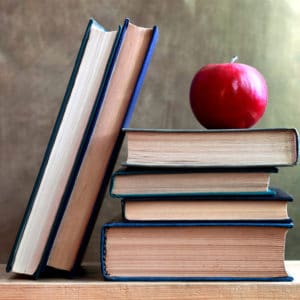 Education Career Cluster image of horizontal and vertically stacked books with a red delicious apple on top