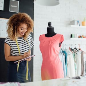 Fashion Designer Career - woman with tape measure working with a dress on a mannequin