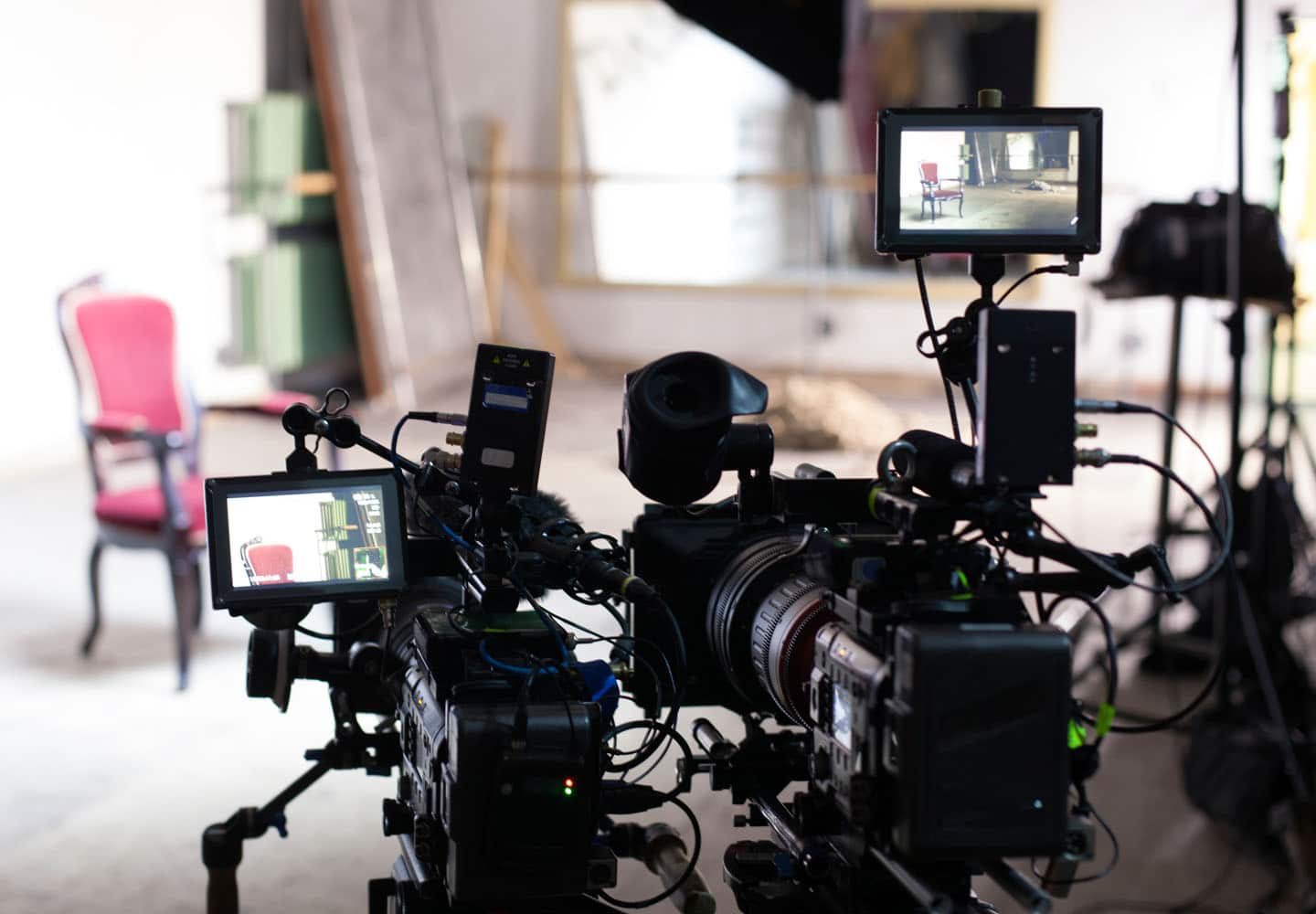 Video cameras and monitors on tripods focused on living room film set
