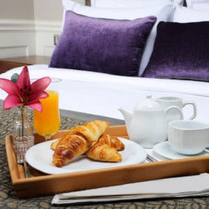 Hospitality & Tourism Career Cluster image of plush hotel room with room service breakfast croissants and orange juice