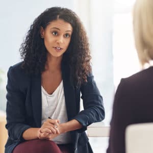 Woman industrial organizational psychologist discusses a strategy or problem with fellow workers in a company office