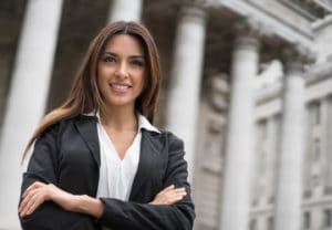 Woman attorney in black robe standing in front of a judicial court building