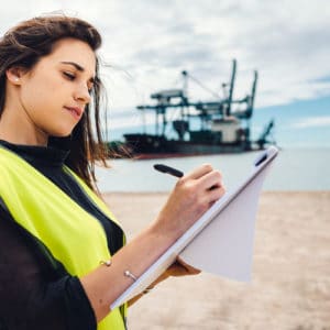 Marine Engineer taking notes in front of ship