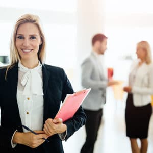 Woman sales manager in a professional white shirt and navy jacker stands in a showroom and holds a clipboard in her hand