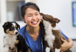 Veterinarian major - smiling woman holds two dogs.