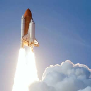 Aerospace engineer designed red and white space shuttle rocket launches into space against a blue sky and cloud