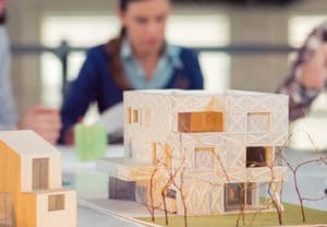 Architecture College Major - Woman designing a model building out of wood and paper