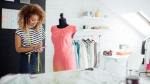 Fashion Designer Career - woman with tape measure working with a dress on a mannequin