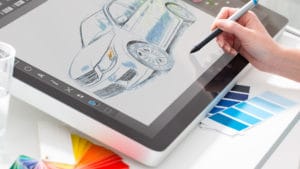 Woman industrial designer draws with a stylus to create a new automobile design on an interactive screen tablet pad