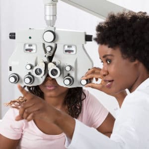woman ophthalmologist inside a doctor's office a white coat adjusts a vision testing machine in front of a patient's eyes