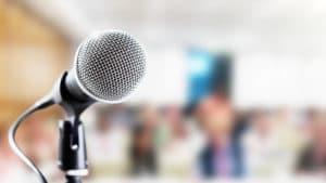 Public relations specialist silver microphone attached to a black mic stand ready for an announcement to the audience