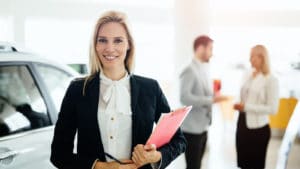 Woman sales manager in a professional white shirt and navy jacker stands in a showroom and holds a clipboard in her hand