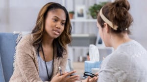 Woman school counselor sits a school table and counsels a student about a problem she needs guidance about