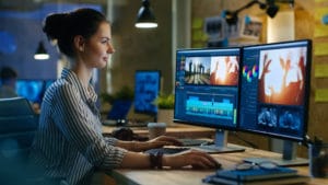 woman editing film in front of two video monitors