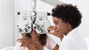 woman ophthalmologist inside a doctor's office a white coat adjusts a vision testing machine in front of a patient's eyes