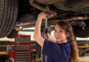 Automotive Engineering Technology Major - Woman with a tool in automotive garage fixing the underside of a raised car