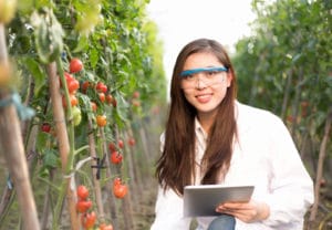 Biological & Agricultural Engineering College Major - Woman wearing white lab coat holds a notepad in a field of plants