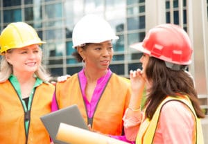 Construction Management College Major - 3 Women with hard hats discuss construction plans on a construction site