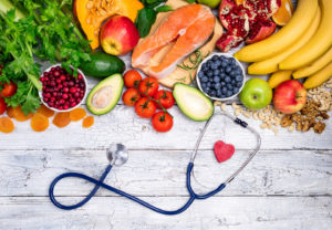 Fresh colorful variety of fruit on wooden table next to a stethoscope and heart shape