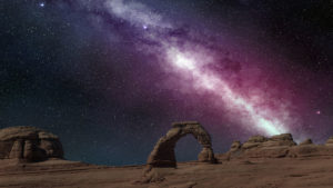 Astronomer image of bright group of white milky way stars against a dark purple space sky with ancient monuments in foreground