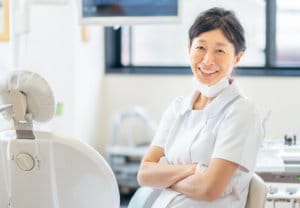 Dentist relaxes in her dental office next to a patient's chair