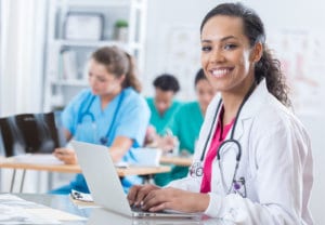 Several women medical students work on laptops in a classroom setting