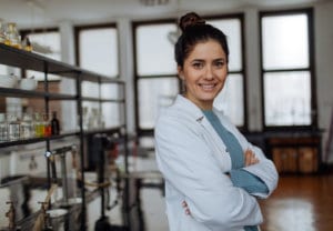 Woman pharmacist smiling in front of shelves with pharmacy products