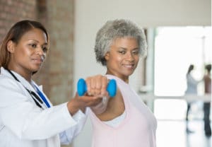 Physical therapist helps senior woman with wrist injury