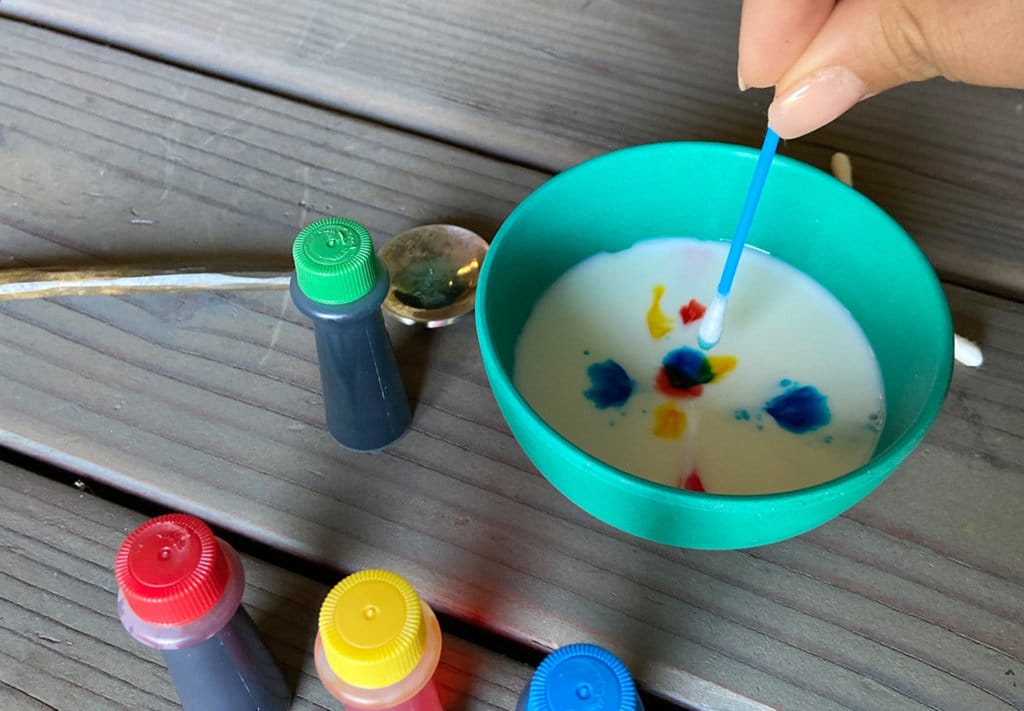 Green bowl with milk and food coloring demonstrating science activity