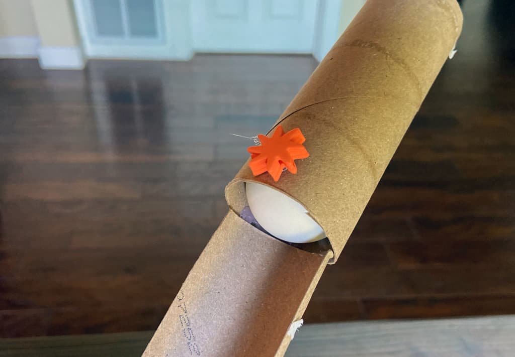 Ping pong ball going through cardboard tube at top of obstacle course activity