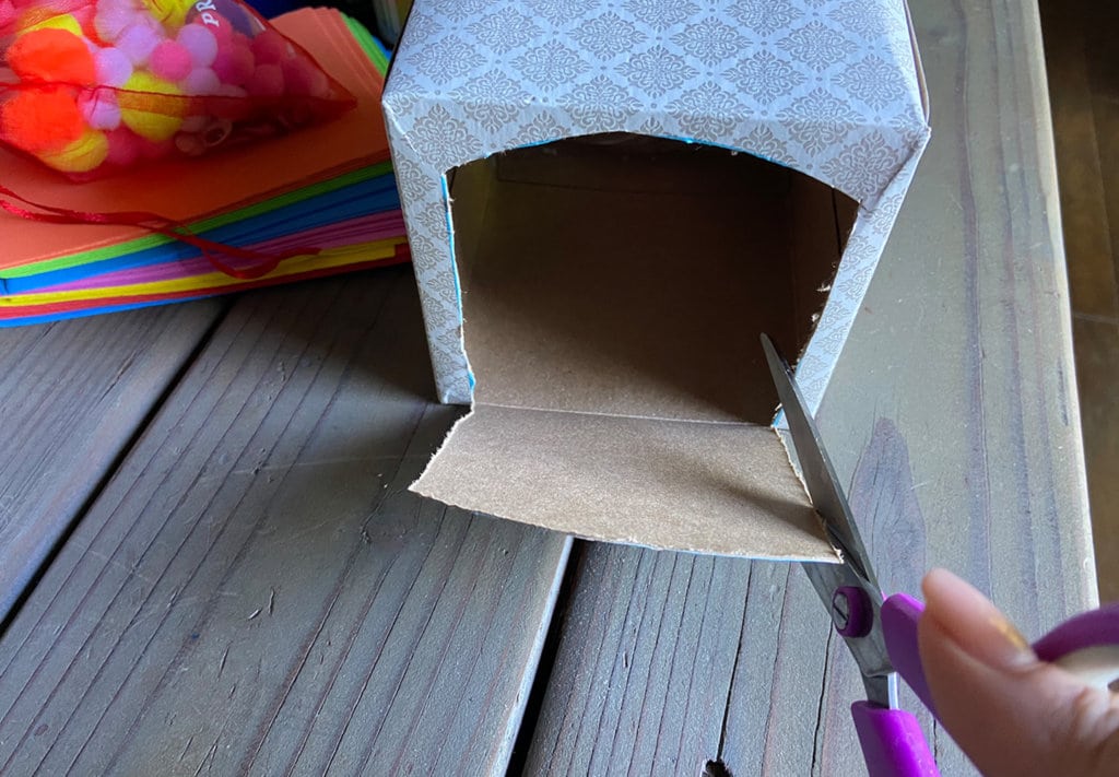 Cutting the cardboard tissue box to create an opening for the obstacle course track