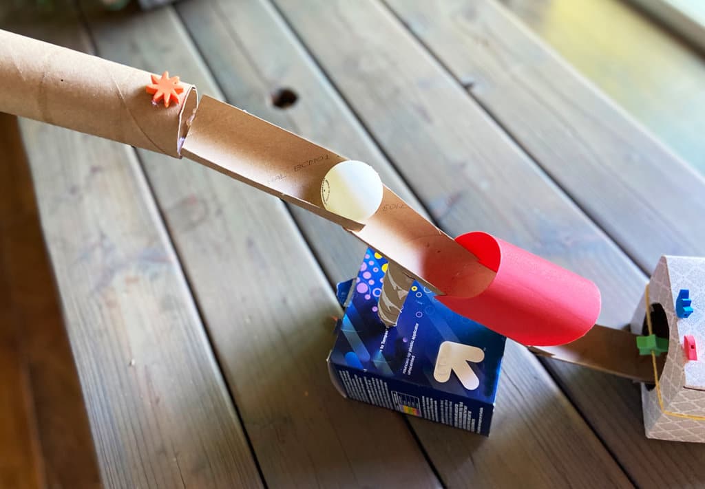 Midway ping pong ball going through cardboard tube at top of obstacle course activity